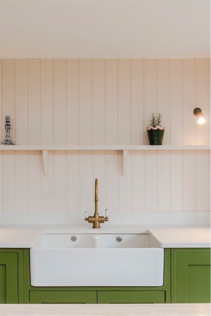 Green kitchen with brass tap and butler sink