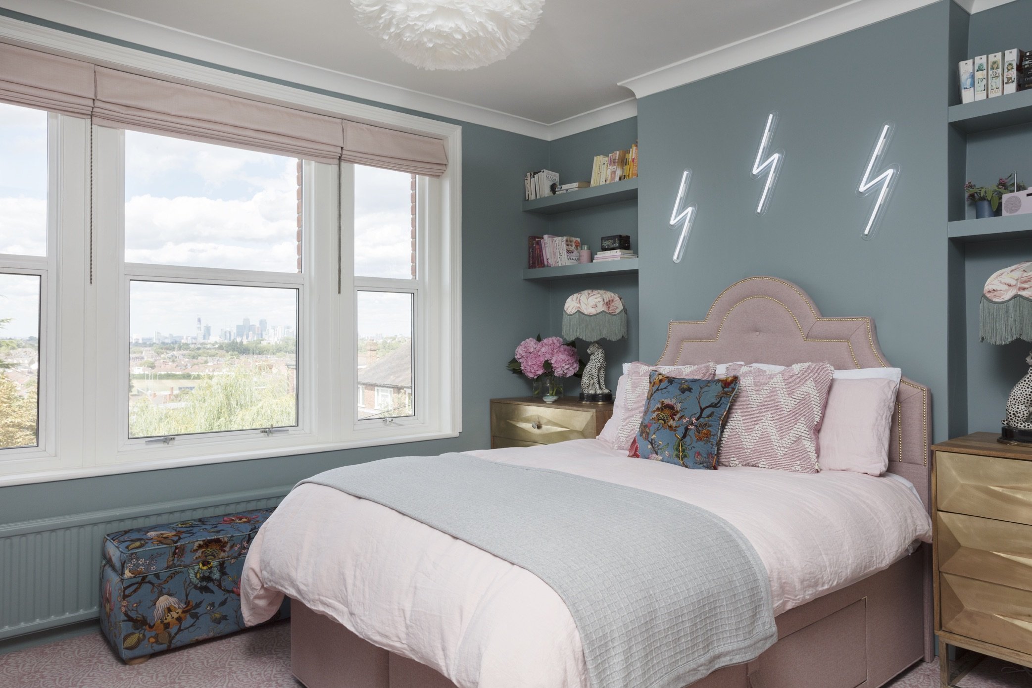 Pink and blue bedroom with pink headboard and neon art